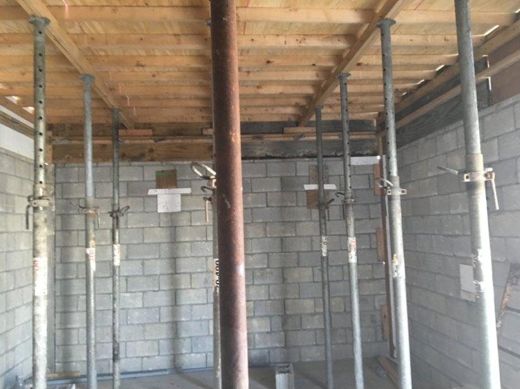 Inside the new walls, props holding the roof deck while the concrete cures.