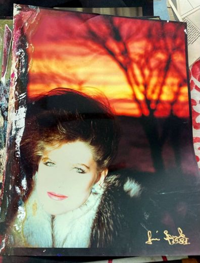 A fur collar and the sunset behind her, signed by the photographer in the corner.