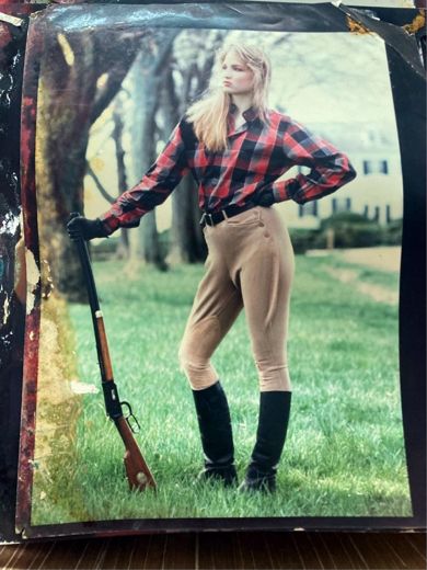 Plaid shirt, breeches and boots, a shotgun for a prop, with the house behind.